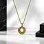 A gold ayat al kursi pendant for men necklace with an intricate circular filigree design, hanging from a gold chain